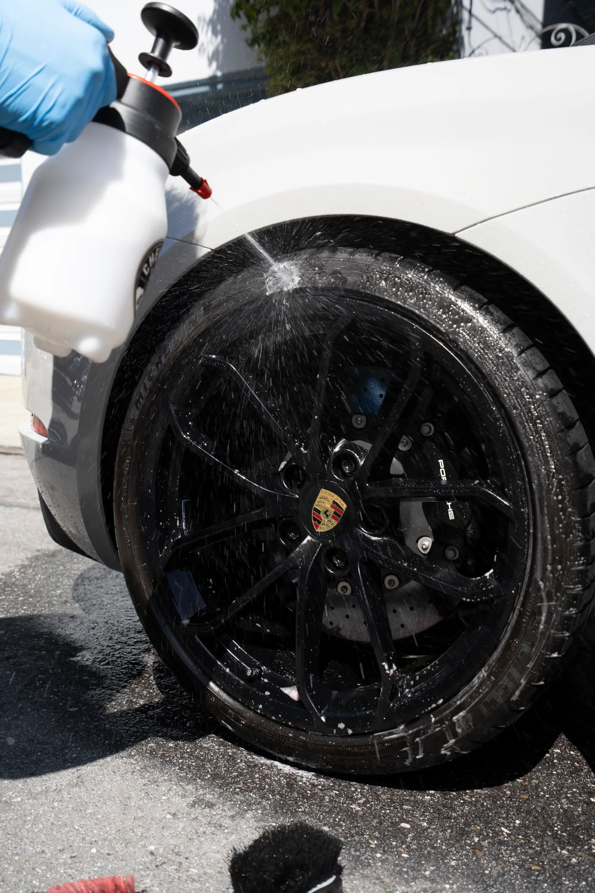 Porsche 718 Spyder, Spraying wheel cleaner on Porsche 718 black wheel with Porsche-crest center cap