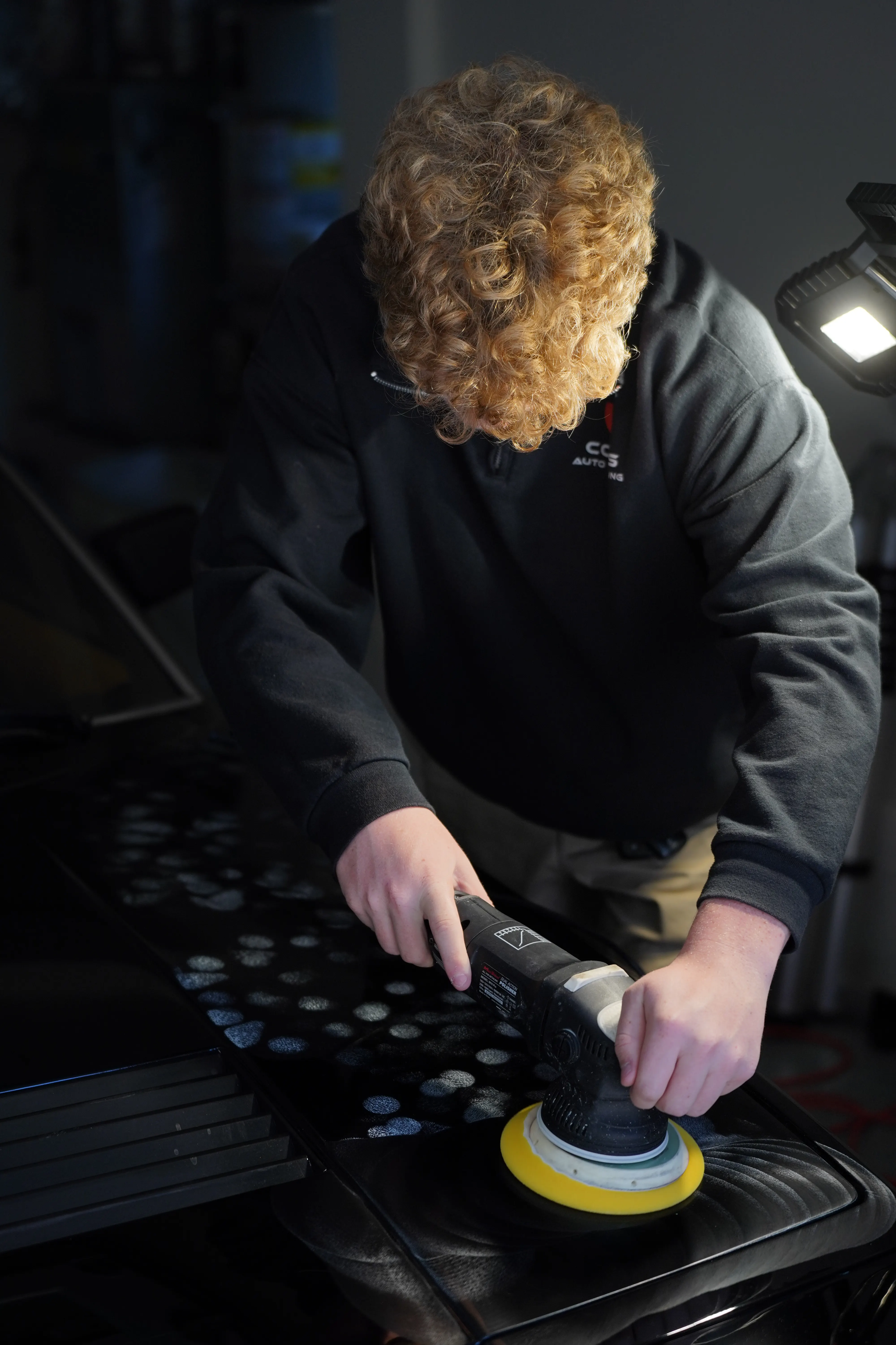 Machine polisher correcting the paint of a black Ferrari 400i
