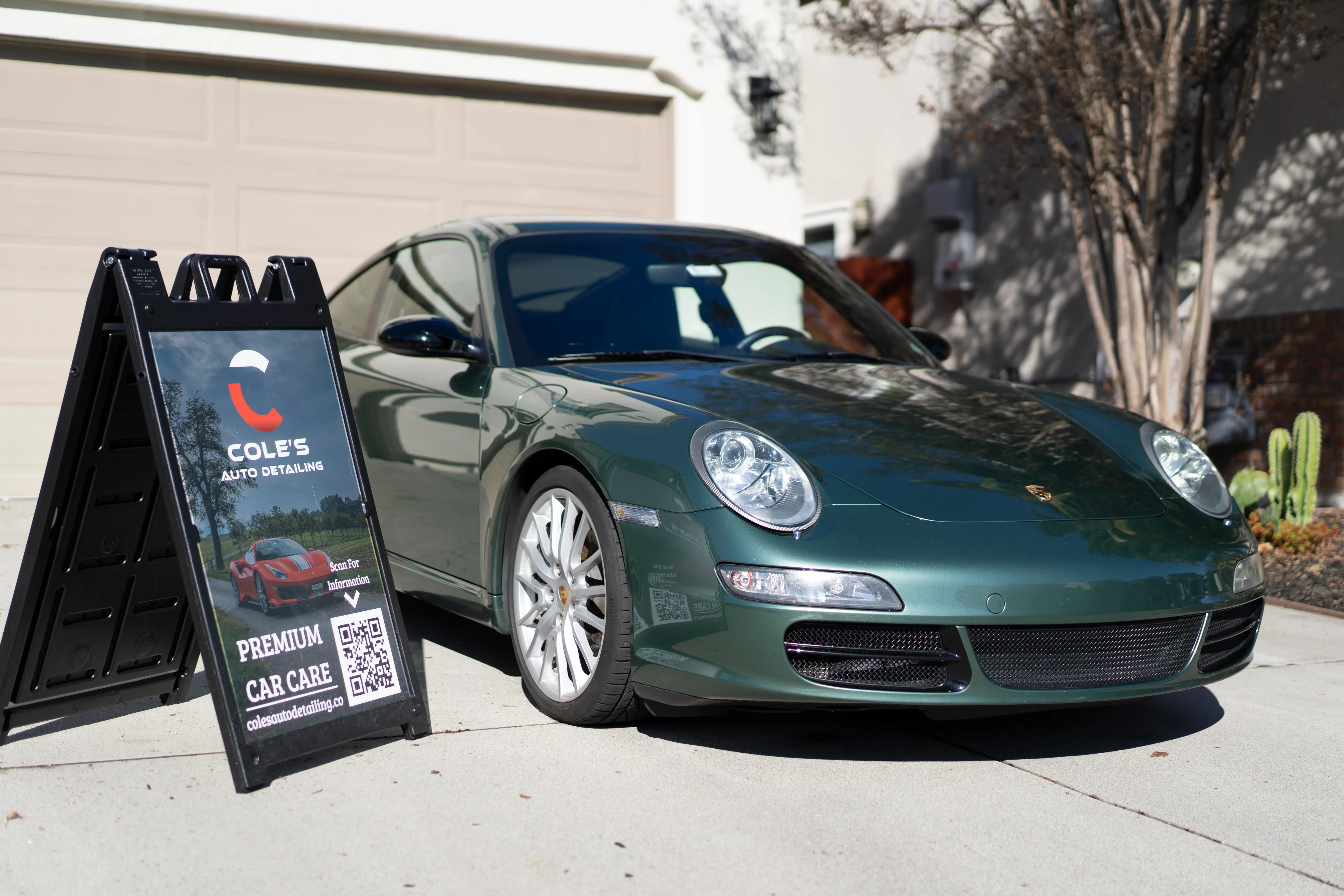 Green Porsche 911 beside the Cole's Auto Detailing sign