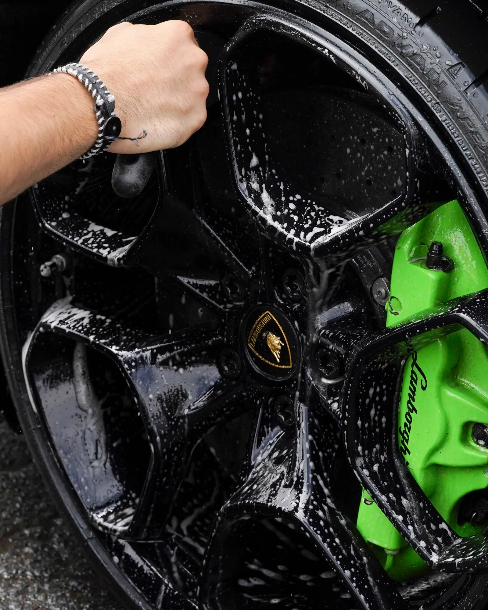 Hand-washing a Lamborghini Huracán wheel over its green caliper