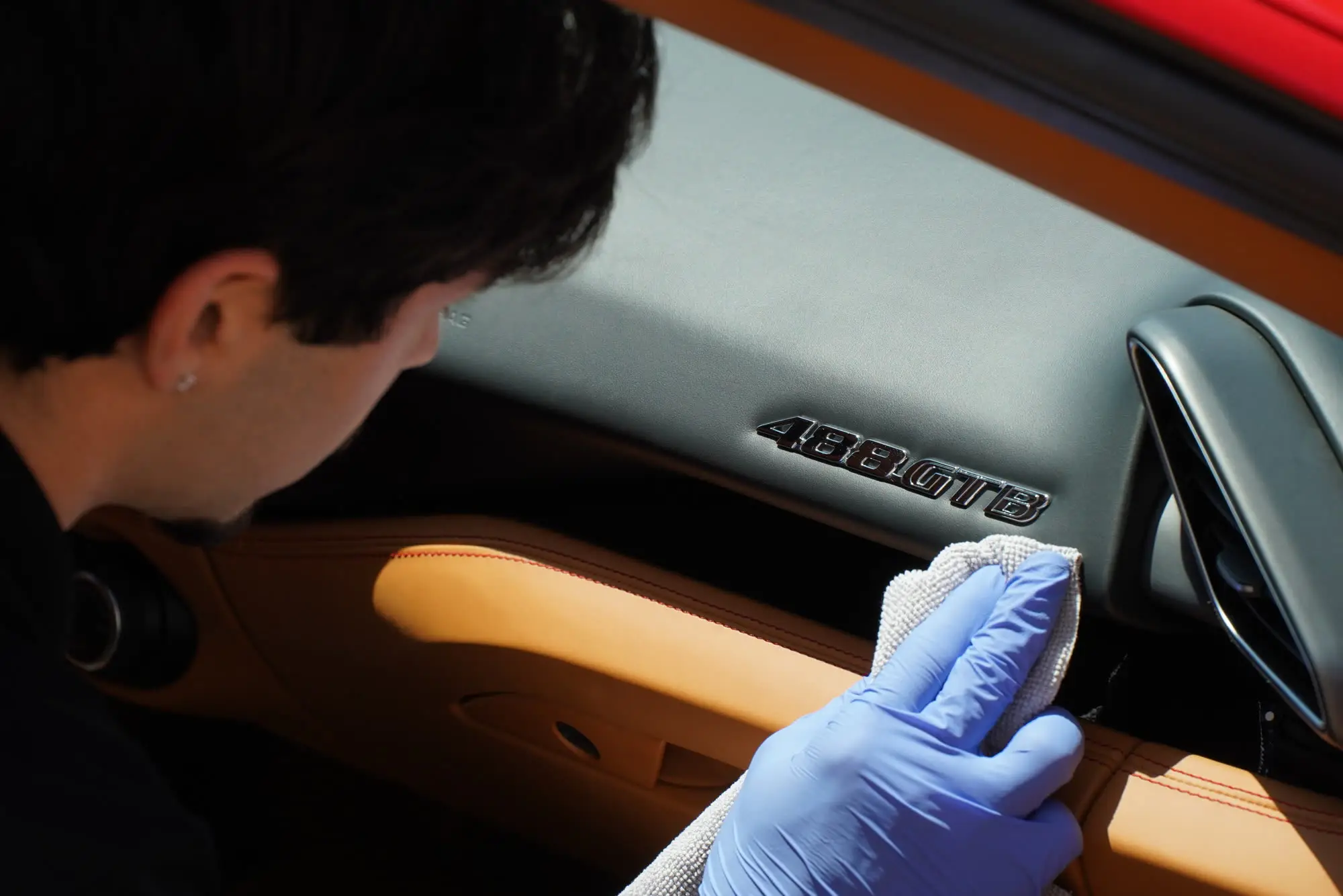 Ferrari 488 GTB, Detailer wiping 488 GTB dashboard badge, tan leather door