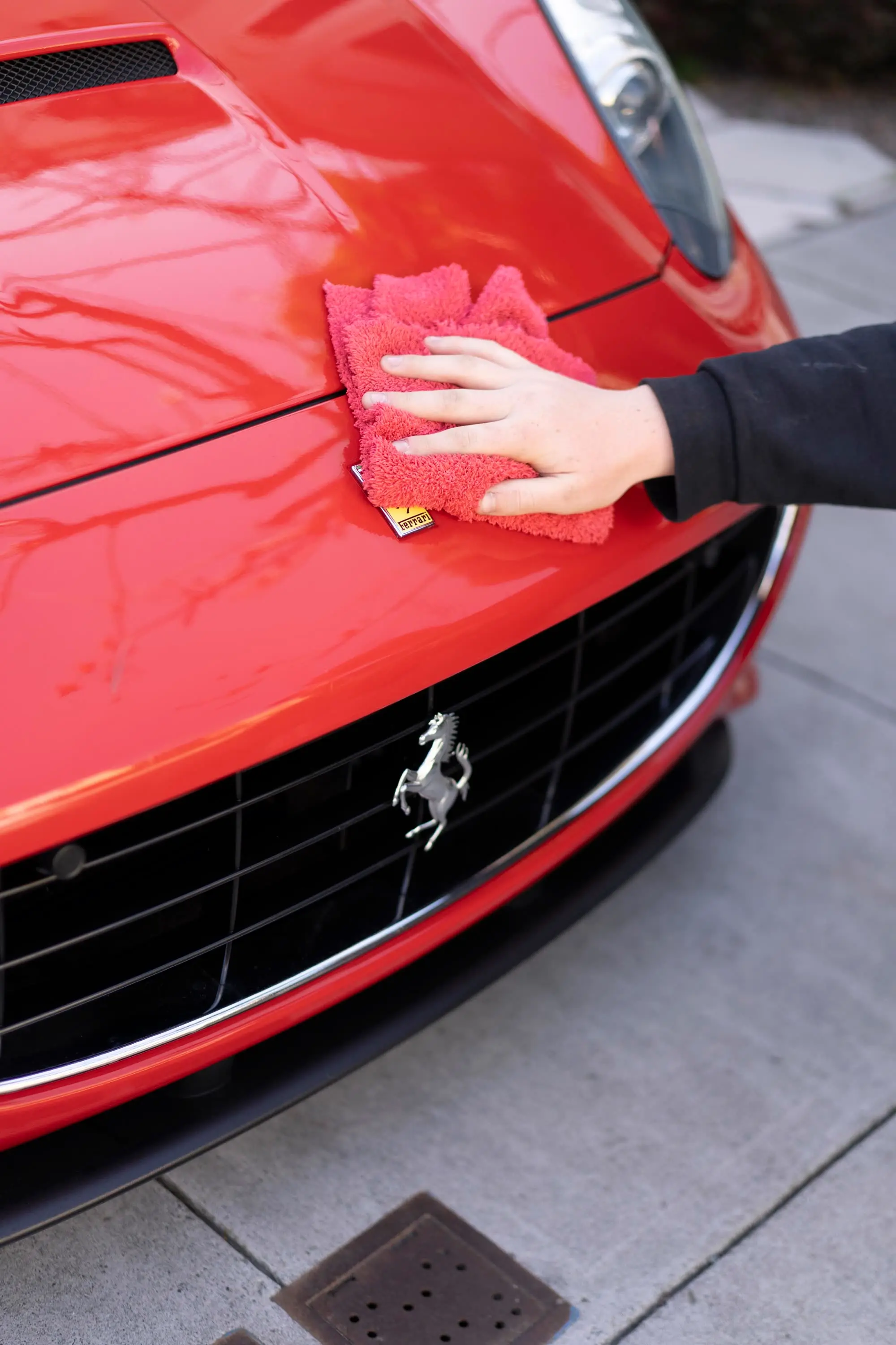 Ferrari California, Hand wiping Ferrari hood with red microfiber towel above grille