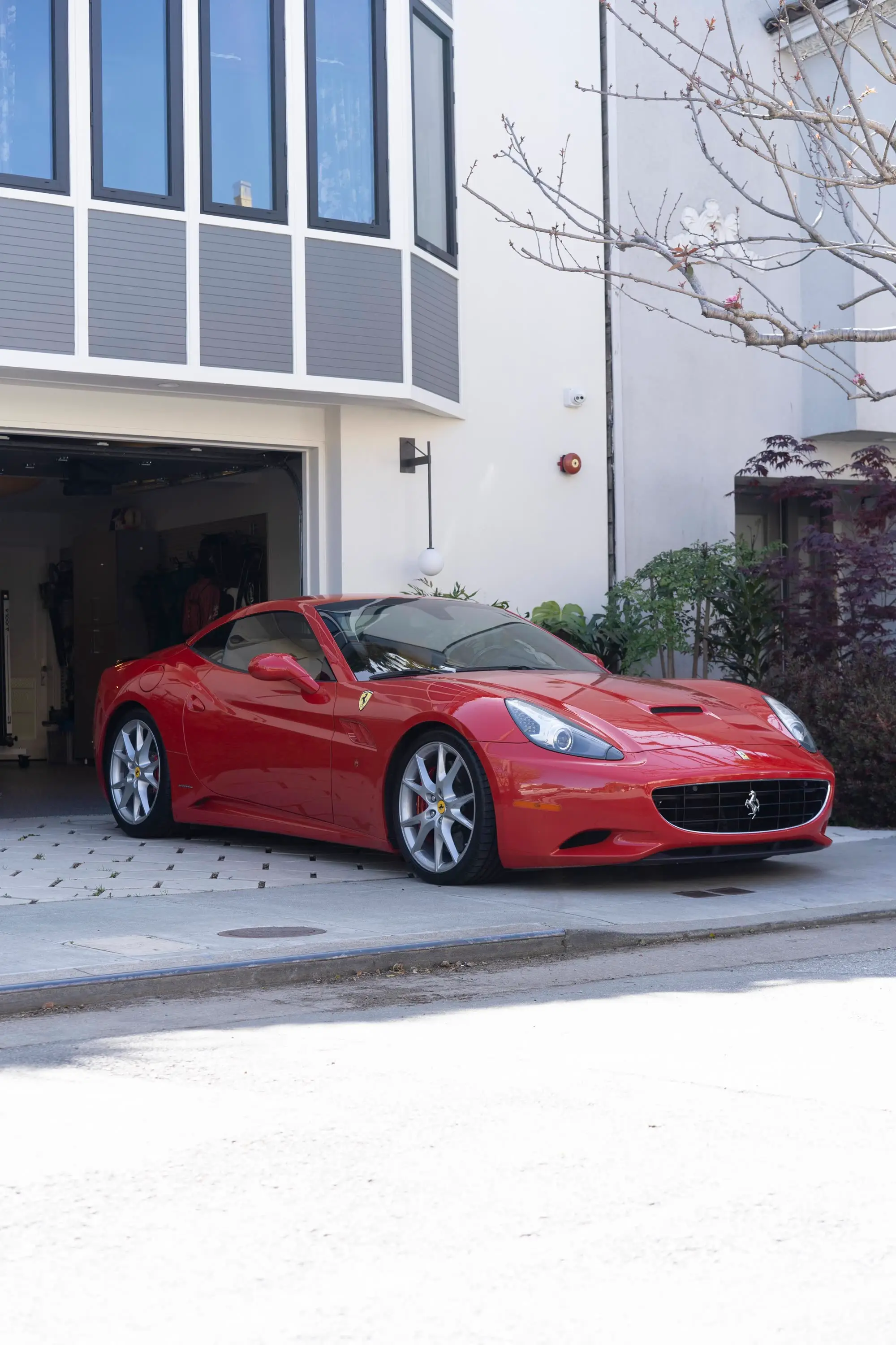 Ferrari California parked in front of modern garage/townhouse